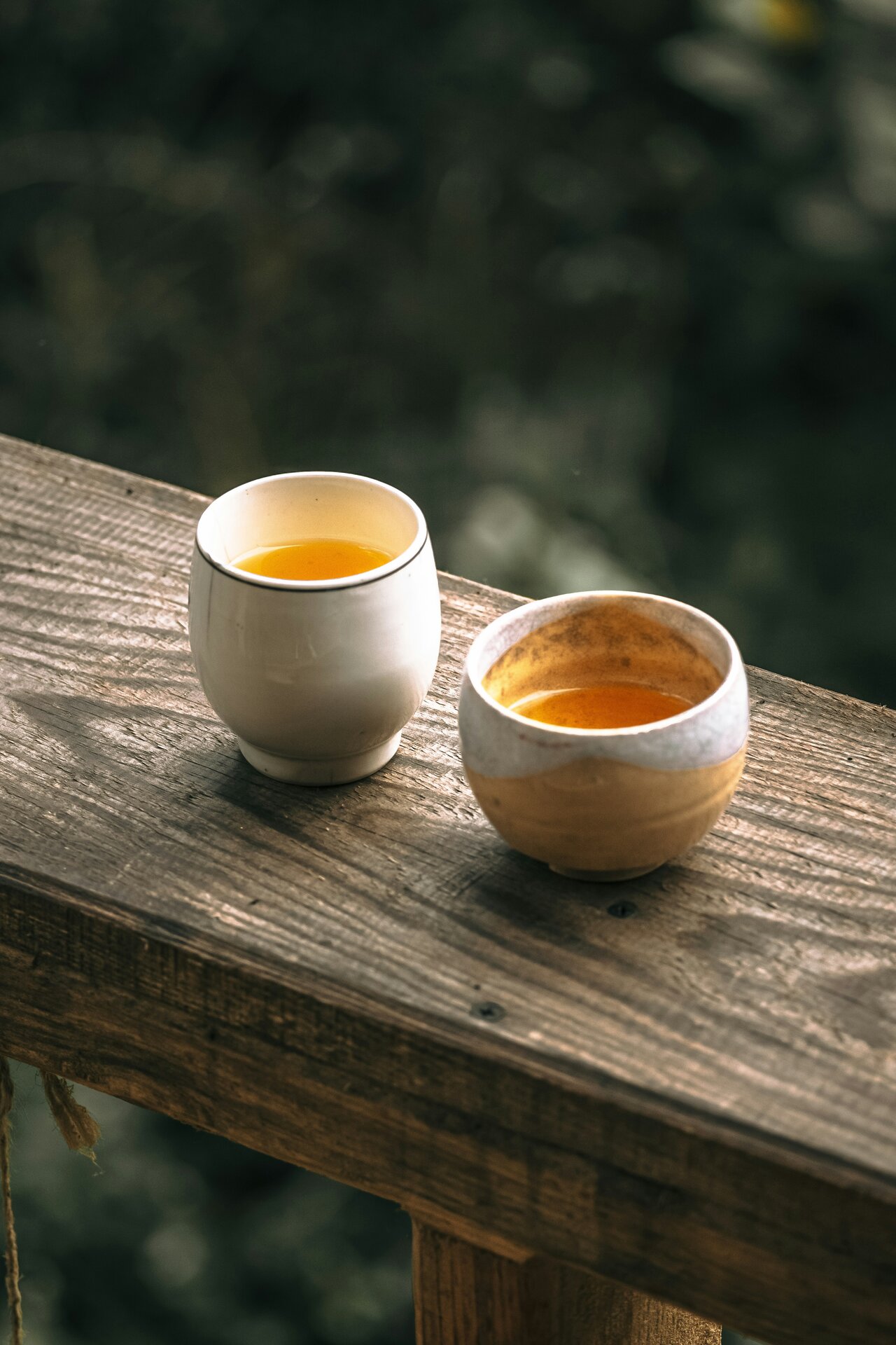 Two ceramic cups on wooden railing